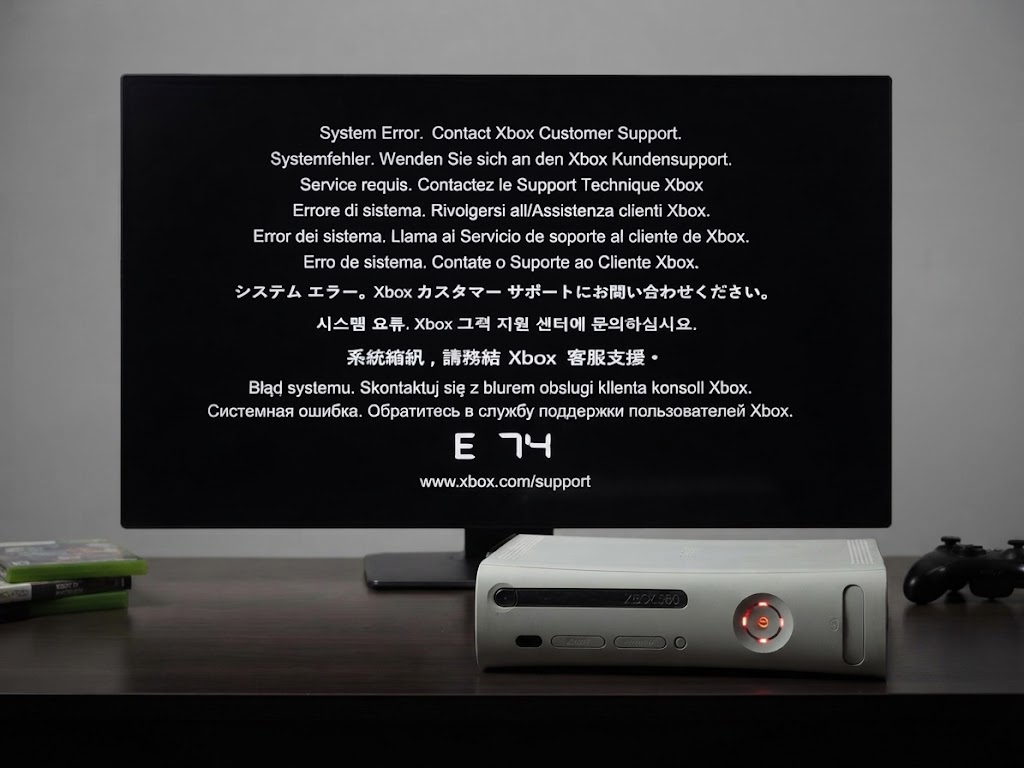 Televisão com o ecrã de erro E74 de uma Xbox 360, com a consola ligada à frente